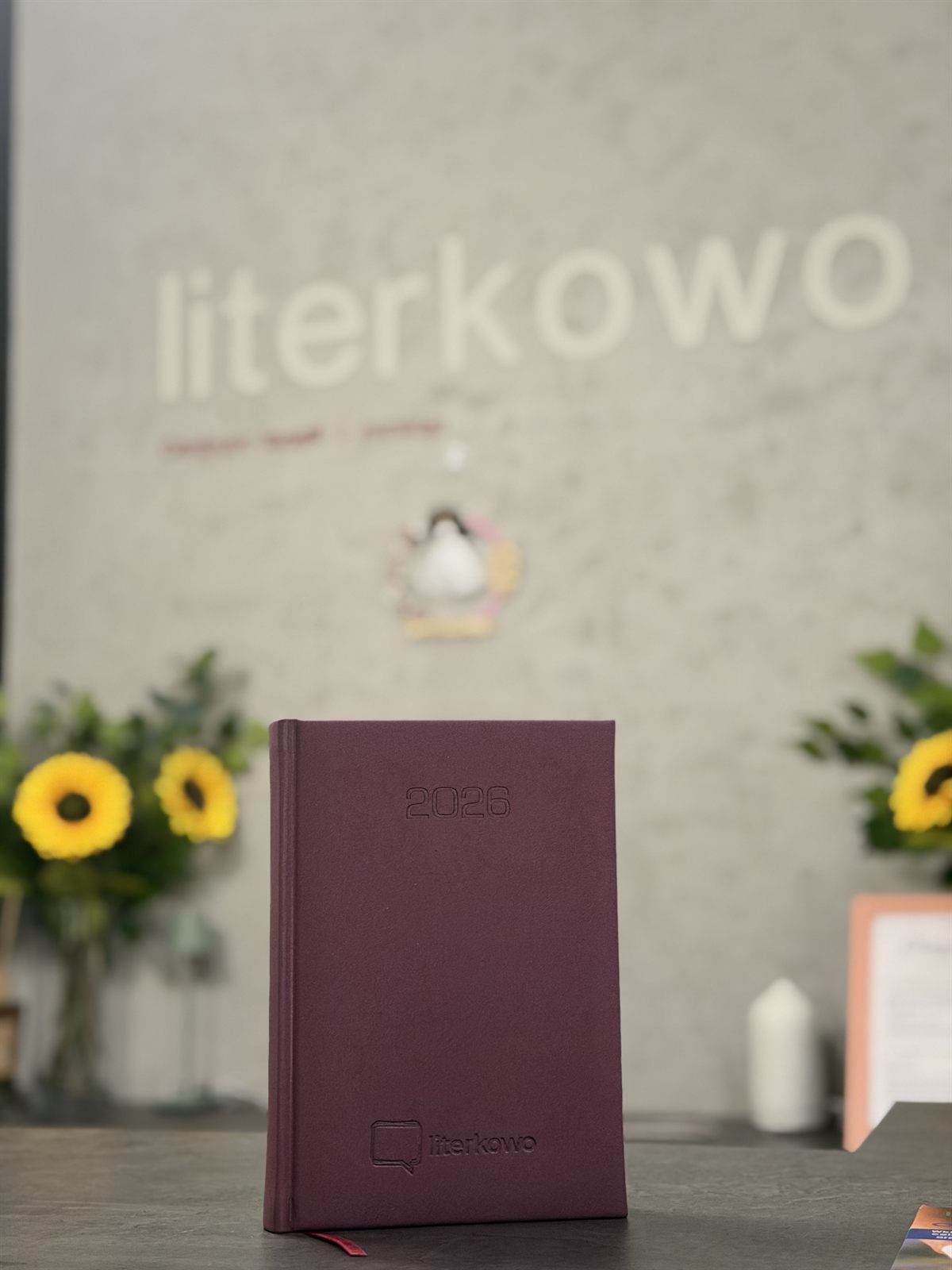 Firmowy kalendarz Literkowo na tle ściany z logo